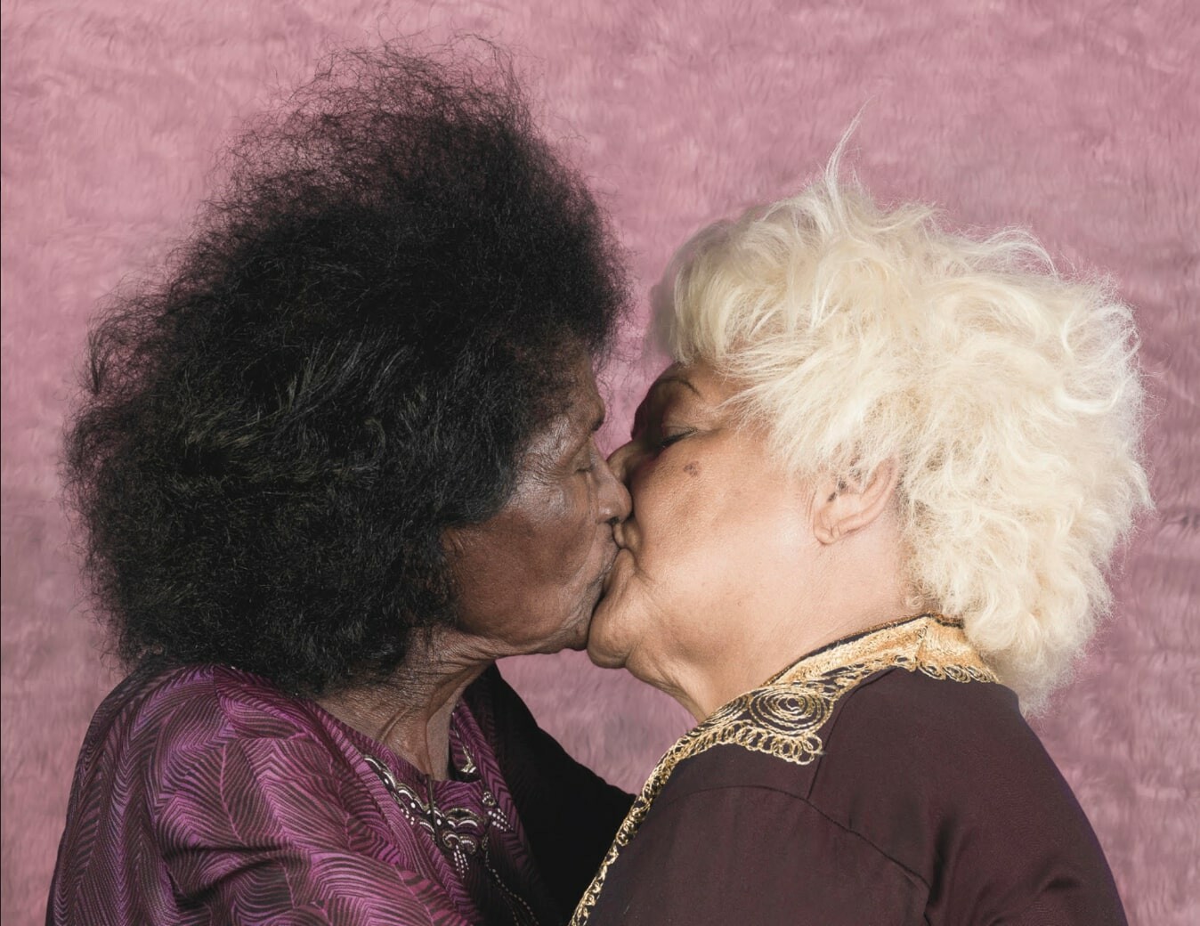 Photo by Enrique Rottenberg of two elderly ladies kissing on the lips.