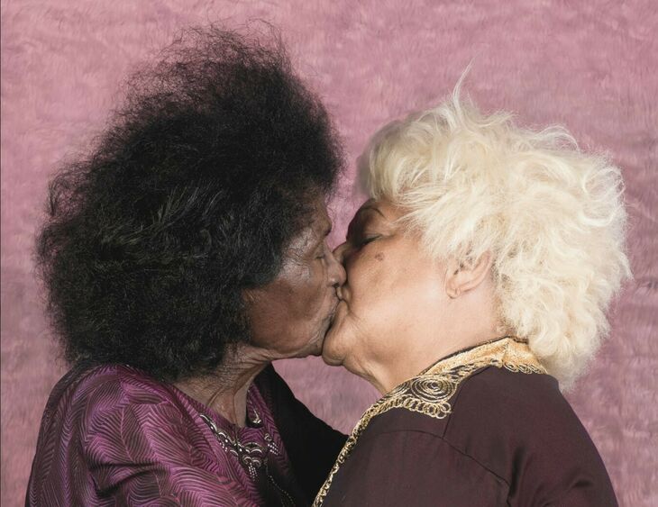Photo by Enrique Rottenberg of two elderly ladies kissing on the lips.